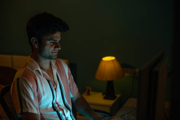 istock Young man working over computer in home office at night 1491547999