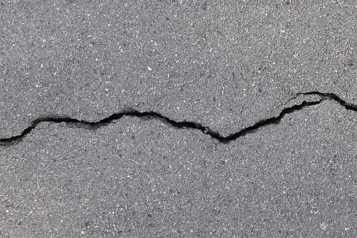 top view of breaking tarmac asphalt road surface, earthquake effect causes ground to damaged, abstract texture background