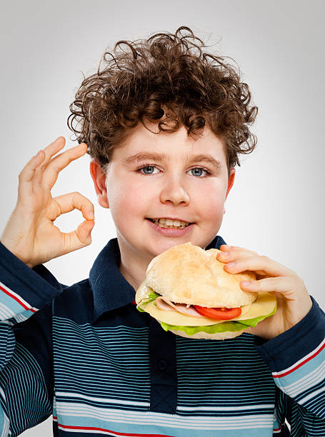 istock Boy eating hamburger showing OK sign 149154854