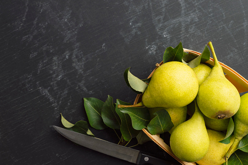 Fresh bio pears with leaves.Fresh pears in the tray. On wooden background. Fresh ripe pears.Space for text. Top view, flat lay. Copyspace. Banner.