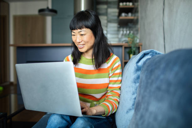istock Young Japanese Woman using a laptop at home on the couch 1491549785