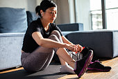Young Japanese woman tying her shoelaces and getting ready to go exercise