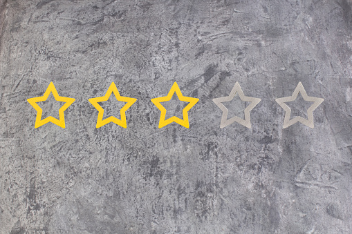Gold, gray, silver five star shape on the gray concrete background. The best excellent business services rating customer experience concept. Concept image of setting a five star goal. Increase rating or ranking, evaluation and classification idea