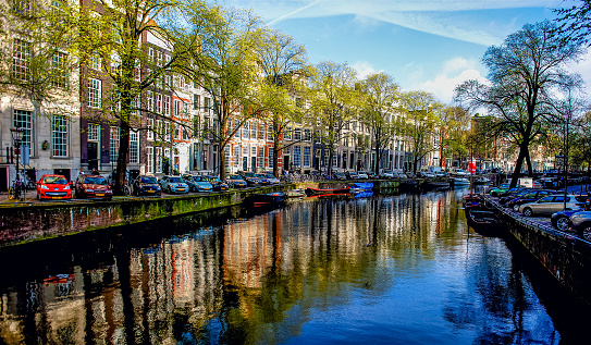 Views of the always present canals in Amsterdam, Netherlands, lines with both residential and commercial buildings and walkways for pedestrians and bicycles.