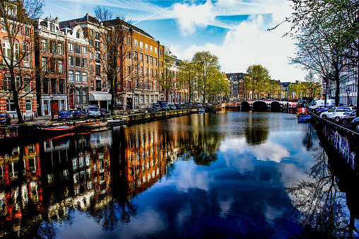 Views of the always present canals in Amsterdam, Netherlands, lines with both residential and commercial buildings and walkways for pedestrians and bicycles.