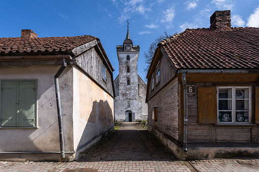 Kuldiga, Latvia – April 10, 2023: Ancient buildings of Raina Street. In the distance the Church of the Holy Trinity of Kuldiga can be seen