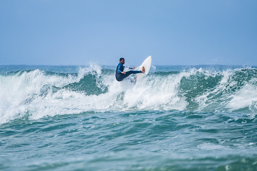 Young athletic surfer rides the wave in Furadouro Beach in Ovar, Portugal.