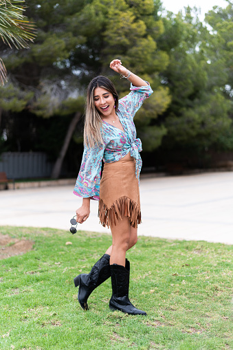 Vertical photo of a beauty and happy fashionable woman in skirt dancing on a garden