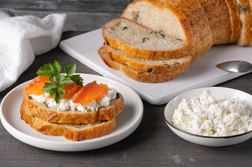 Sandwich with salted salmon and cottage cheese on a gray wooden table.