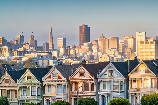 The famous Painted Ladies houses and the San Francisco skyline in California, USA during sunset.