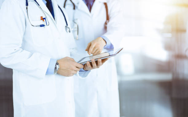 istock Group of unknown doctors  use a computer tablet to check up some medical names records, while standing in a sunny hospital office. Physicians ready to examine and help patients. Medical help, insuranc 1491564823