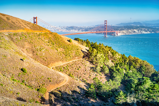 Winding dirt road leading towards the landmark Golden Gate Bridge at Golden Gate National Recreation Area, San Francisco, California, USA.