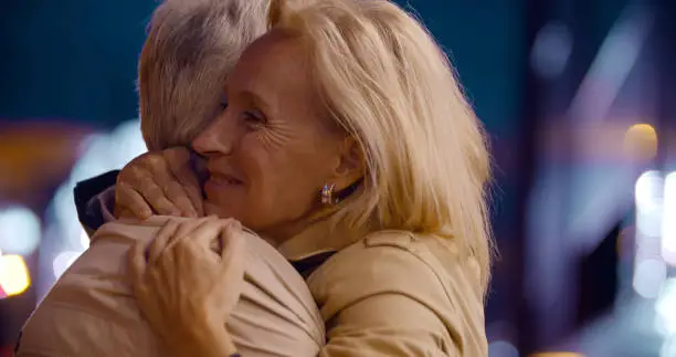 Photo of Bokeh shot of happy senior couple hugging in city at night