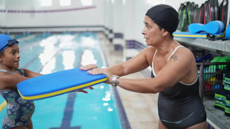 Teacher teaching how to swim to students in the poolside