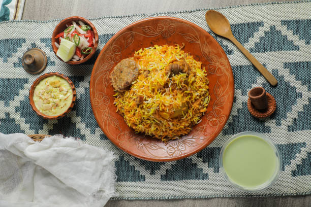 Mutton Kacchi biryani with salad, borhani and Chui Pitha served in dish isolated on mat top view of indian and bangladeshi food