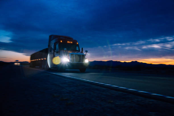 As the sun began its descent, casting a warm golden hue across the Nevada Desert, a mighty semi-truck rumbled through the vast expanse. Its sleek silver body contrasted against the barren landscape, while the mountains in the distance stood tall and majestic. Dust kicked up in the truck's wake, creating a swirling trail that danced with the fading light. The driver's steady hand guided the vehicle through the winding road, a solitary figure against the breathtaking backdrop. As the sun dipped below the horizon, painting the sky in vibrant oranges and purples, the semi truck pressed on, carrying its cargo through the tranquil desert evening. al atardecer, un camión de 18 ruedas atravesó el desierto de nevada, levantando polvo a su paso. las escarpadas montañas formaron un impresionante telón de fondo, mientras el camión continuaba su viaje solitario a través de la vasta extensión.