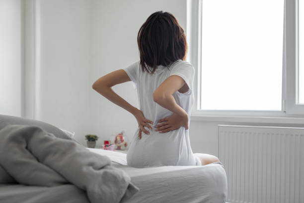 Woman feels back pain massaging aching muscles Woman feels back pain massaging aching muscles lower back pain stock pictures, royalty-free photos & images