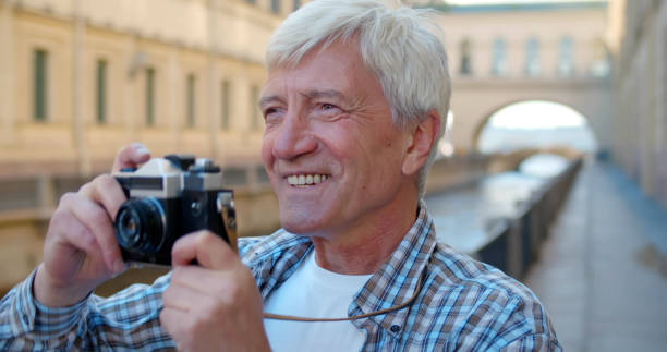 istock Senior man tourist standing outdoors with vintage camera 1491570078