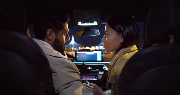 Diverse beautiful young couple sitting on front seats in car Diverse beautiful young couple sitting on front seats in car. Back view of successful woman and man in love talking and smiling sitting in car couple driving at night stock pictures, royalty-free photos & images