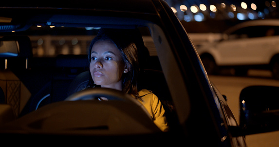 African-American businesswoman in car. Portrait of confident female sitting in car parked outdoors in night city