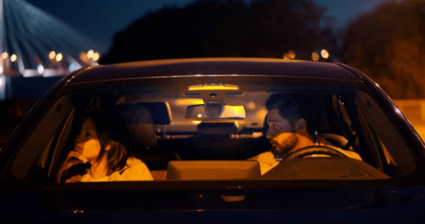 Beautiful diverse couple having an argument in car Beautiful diverse couple having an argument in car. View through windscreen of woman and man sitting in car and having fight couple driving at night stock pictures, royalty-free photos & images