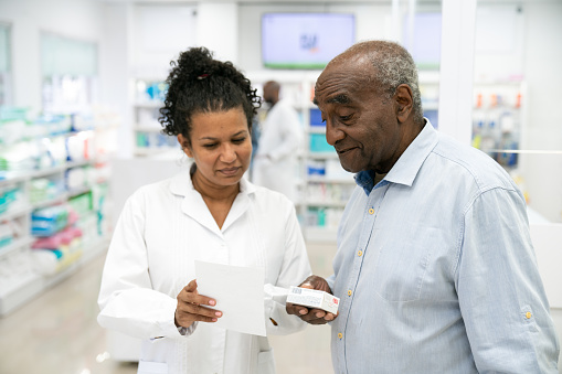 Female pharmacist guiding customer with tablets on digital tablet
