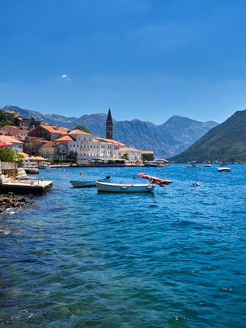 View of the beautiful baroque buildings and the tower of the church of St. Nicholas in Perast, with boats in the Adriatic sea. Kotor bay, Montenegro, Europe