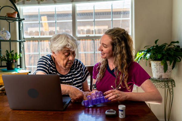 una joven enfermera le está explicando los medicamentos diarios de una anciana. la enfermera parece paciente y atenta mientras discute el régimen de medicamentos con la mujer. - atención residencial fotografías e imágenes de stock