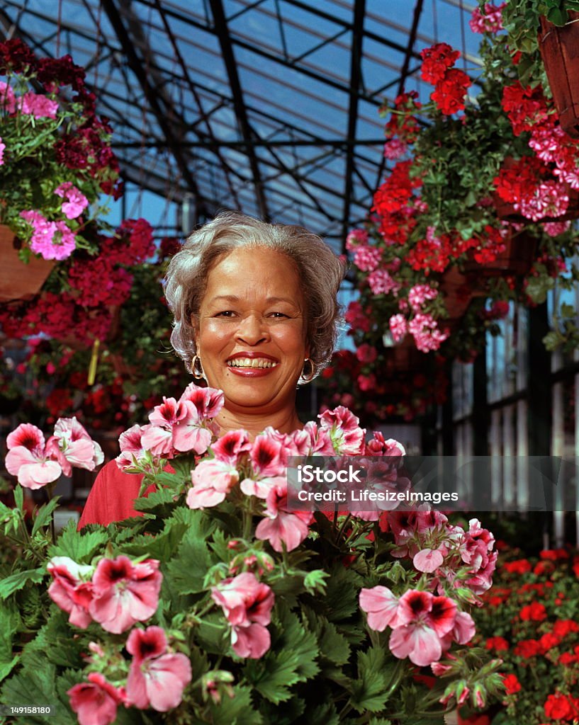 Mulher Madura cercado por plantas florescendo no berçário, Retrato - Foto de stock de 45-49 anos royalty-free