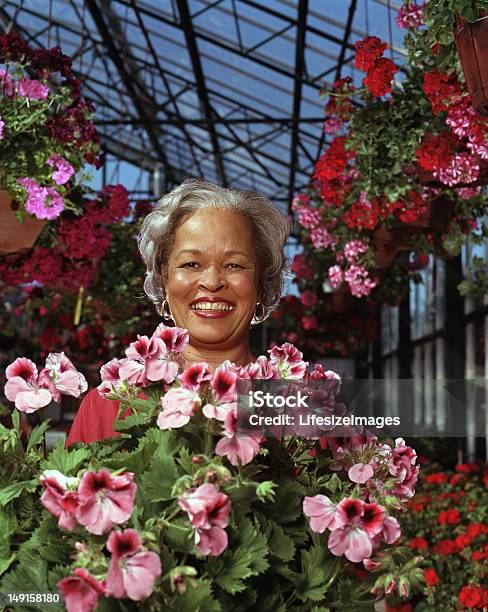 Foto de Mulher Madura Cercado Por Plantas Florescendo No Berçário Retrato e mais fotos de stock de 45-49 anos