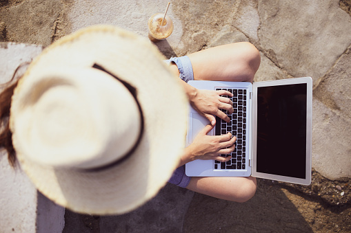 Young woman working with a laptop on nature in summer beach