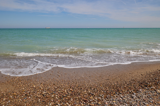 Blue calm sea, waves, sandy beach and pebbles. Balearic Sea, Spain.