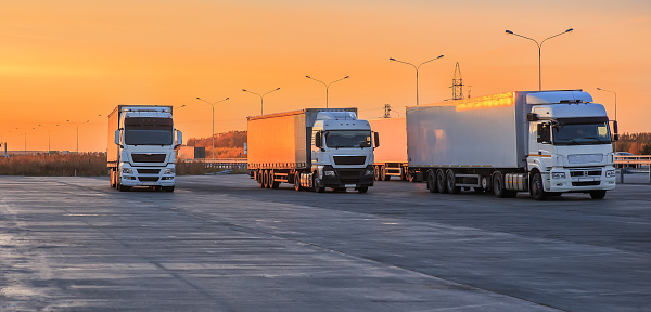 Trucks in a parking lot on a suburban highway at dawn