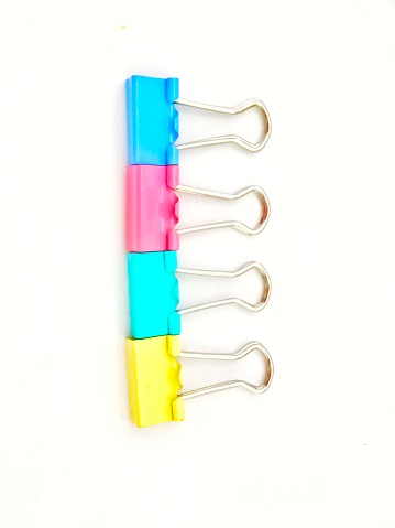 Selective focus of colourful metal binder clips isolated on white background