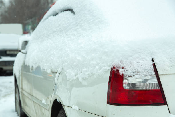 tylny reflektor samochodu z czerwonym światłem stopu pokrytym śniegiem w zimowej pogodzie, zaspami śnieżnymi na drodze i innych samochodach. zbliżenie detalu pojazdu. - car winter road reflector snow zdjęcia i obrazy z banku zdjęć