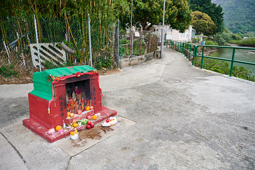 Hong Kong - April 02, 2023: a small road side shrine, with fruits and food offerings in Tai O village.