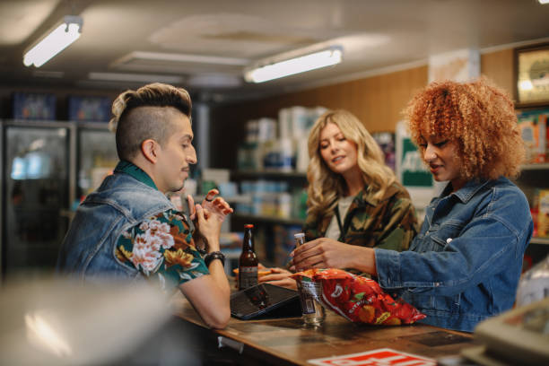 friends shopping in a local store in LA Group of women hanging out, shopping for drinks and snacks in a local convenience store in Los Angeles, California. liquor store counter photos stock pictures, royalty-free photos & images