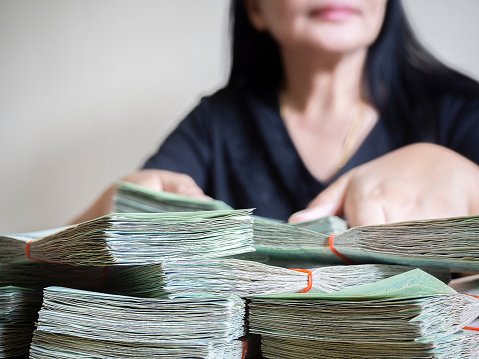 Asian business woman counting money cash in office.  Businesswoman recount money banknotes at workplace. Smiling woman receiving salary in cash.