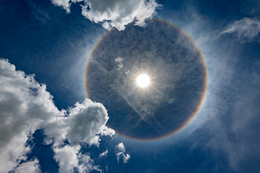 Natural optical phenomenon of sun with halo.Full circle halo around Sun at noon produced by light from the Sun interacting with ice crystals suspended in the atmosphere.There is also flare light.