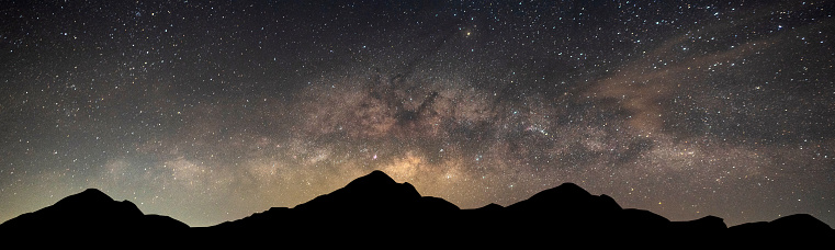 Milky Way. Night sky with stars and silhouette of Mountain Space background.Universe filled with stars, nebula and galaxy with noise and grain.Photo by long exposure and select white balance.