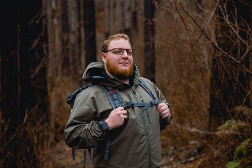 Young caucasian outdoorsman hiking with a backpack in a waterfall area in the Columbia River Gorge in the Pacific Northwest. Taken at Elowah Falls in Oregon.