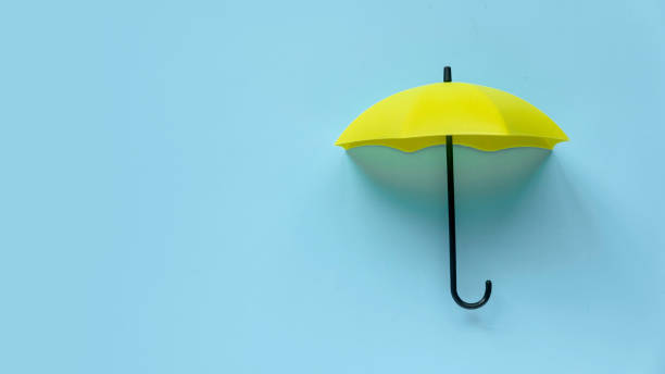 istock Yellow umbrella over a blue background. Banner with copy space. 1491620422