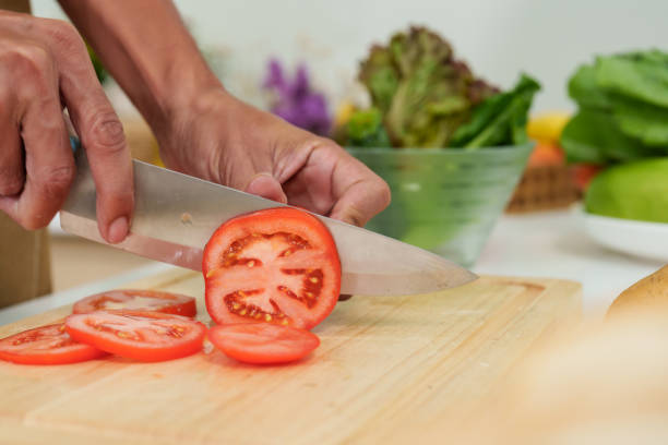 istock Close-up beautiful round red tomato on cutting board, Man cooking in kitchen during holidays who doesn't want go out eat, preparing cooking materials make simple meal on boring holiday. 1491626362