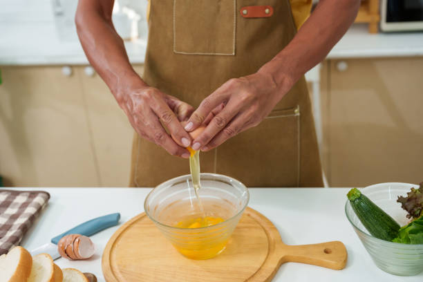 istock Close-up hands young man cooking in kitchen, was hammering fresh chicken egg rim cup, crack fresh chicken egg into cup, with one chicken egg, wanted cook with simple menu with ingredients at home. 1491626372