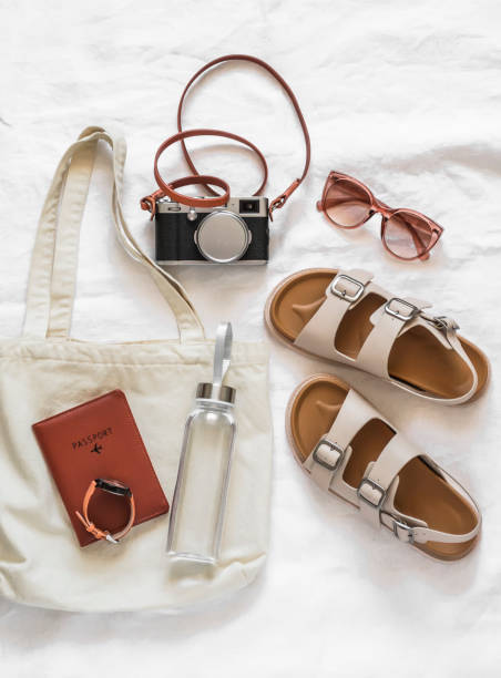 istock Women's accessories for comfortable rest, travel - canvas shopper, camera, comfortable leather sandals, sunglasses, water bottle on a light background, top view 1491634917