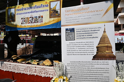 Chiangmai, Thailand – May 20, 2023: scraps from the pagoda on a table with donate sign and description of Phra That.\n\nupdate on the collapse of Phra That Sri Suphan, going on maintenance of Phra That Sri Suphan pagoda in Wat Sri Suphan on Wua Lai Road collapsed in September 2022. Wat Sri Suphan Temple is placed in the Chiangmai province of Thailand.