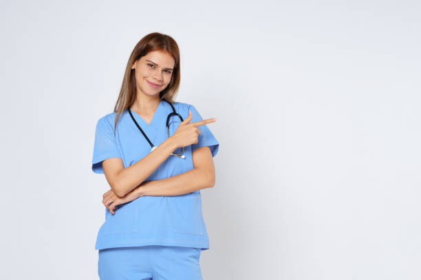 Smiling female doctor pointing with hand on copy space isolated on white background.