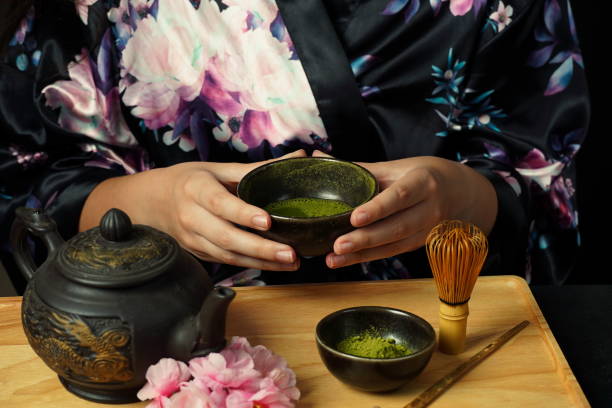 istock Woman tea master in kimono performs tea ceremony. Matcha green tea powder with a bamboo whisk and scoop as used in a traditional Japanese tea ceremony. 1491639259