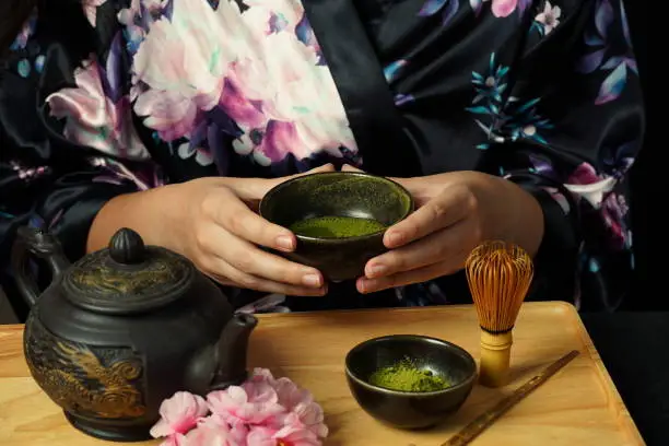 Woman tea master in kimono performs tea ceremony. Matcha green tea powder with a bamboo whisk and scoop as used in a traditional Japanese tea ceremony.