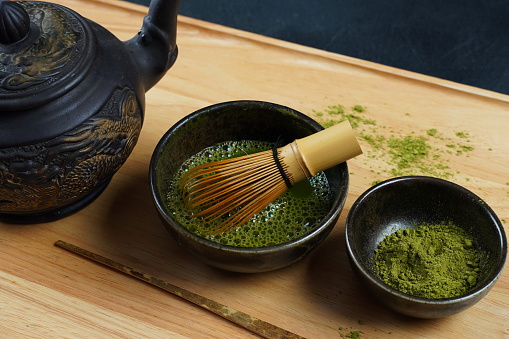 Green matcha tea powder with a bamboo whisk and scoop as used in a traditional Japanese tea ceremony